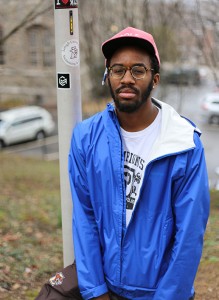 Chester Toye, '17, stands next to the his project symbol sticker on a pole close to Drown Hall on Friday, April 10, 2015. Chester Toye has been working on a photo project related to the bus stops on campus. (Nan He/B&W photo)